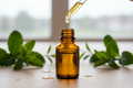 oil dropper dipping in an amber bottle with wintergreen in the background