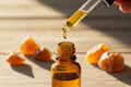 oil dropper dropping essential oil into an amber colored bottle with Amber resin in the background