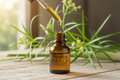 oil dropper dropping essential oil into an amber colored bottle with citronella in the background