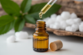 oil dropper dropping essential oil into an amber colored bottle with menthol in the background