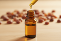 oil dropper dropping essential oil into an amber colored bottle with myrrh in the background