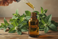 oil dropper dropping essential oil into an amber colored bottle with peppermint in the background