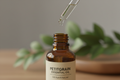 oil dropper dropping essential oil into an amber colored bottle with pititgrain