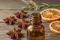 oil dropper dropping essential oils into an amber colored bottle with star anise in the background